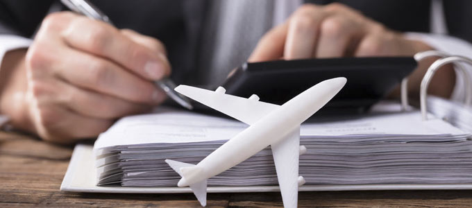 Businessmann mit Kugelschreiber vor einer Akte und einem kleinen weißen Modellflugzeug seine Reisekostenabrechnung machend
