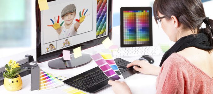 Künstlersozialkasse  / auf dem Foto: Eine Grafik-Designerin sitzt vor dem Computer und probiert verschiedene Farbkompositionen aus.