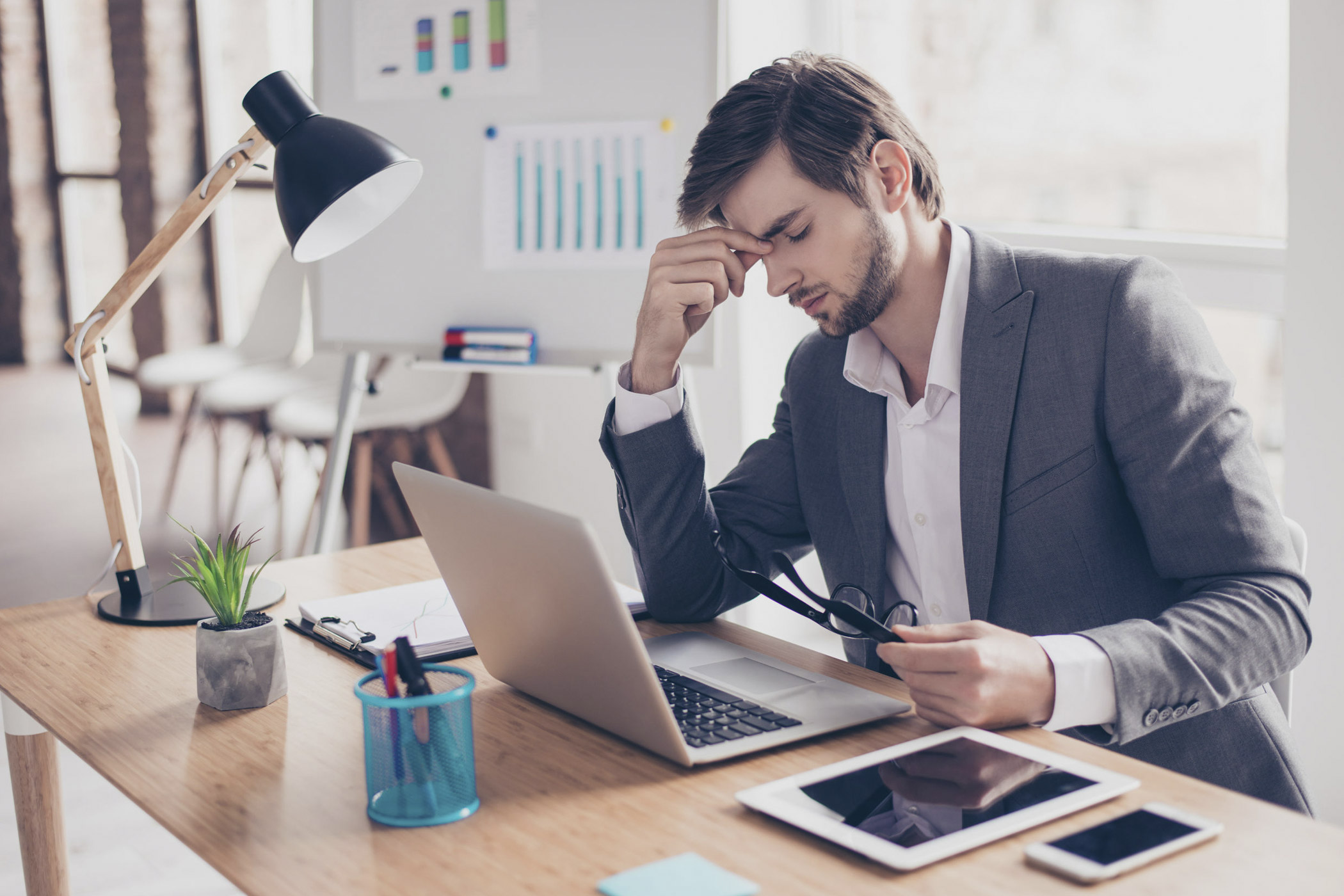 Nicht immer reicht Leistung allein aus, um die Karriereleiter nach oben zu klettern Auf dem Foto: Junger Angestellter, der frustriert und traurig an seinem Arbeitsplatz sitzt