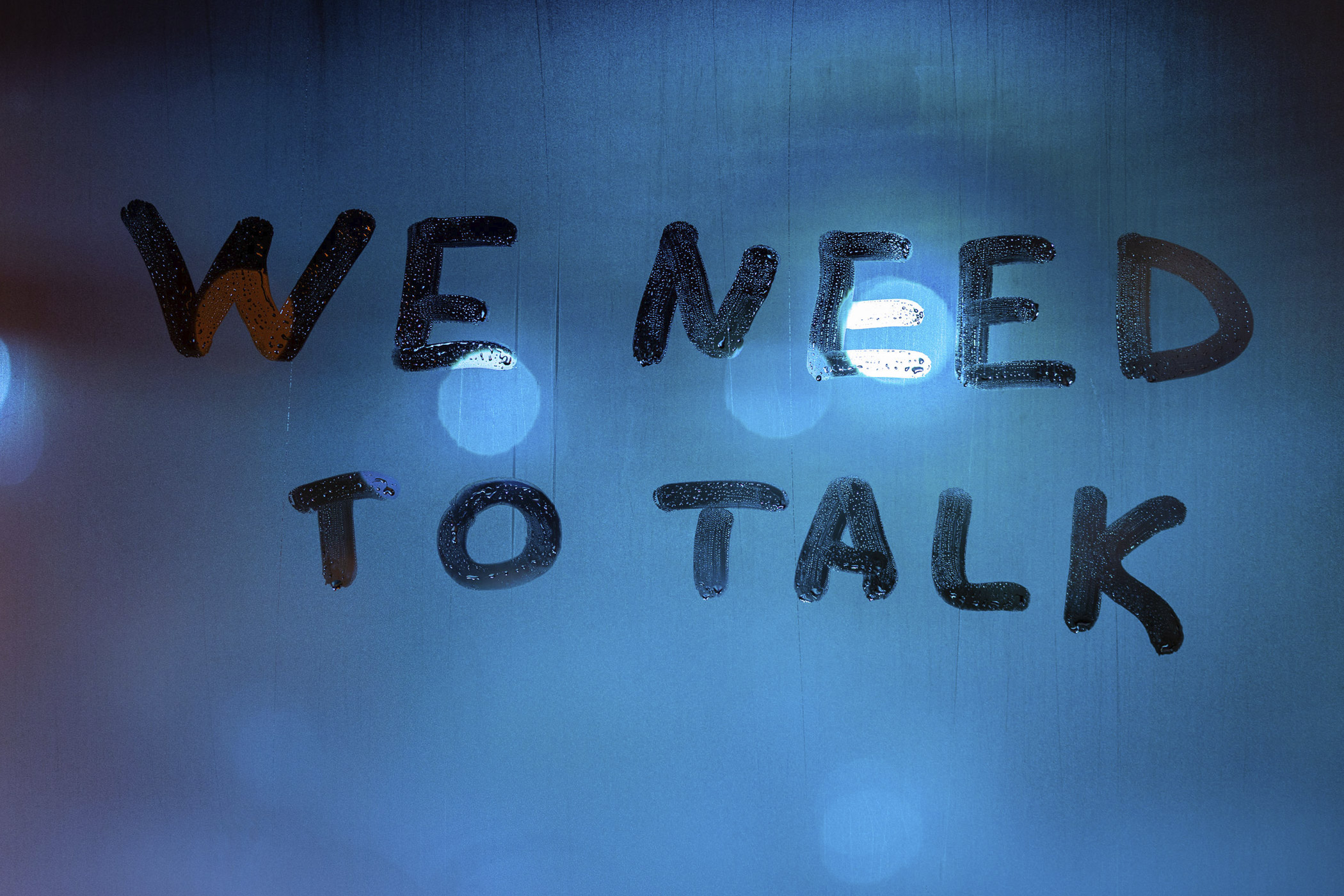 Unangenehme Dinge im Team richtig ansprechen / auf dem Foto: Man sieht "We need to talk" (Wir müssen reden) auf eine beschlagene Glasscheibe geschrieben – Symbol dafür, dass Teamkonflikte offen angesprochen und gemeinsam geklärt werden müssen.