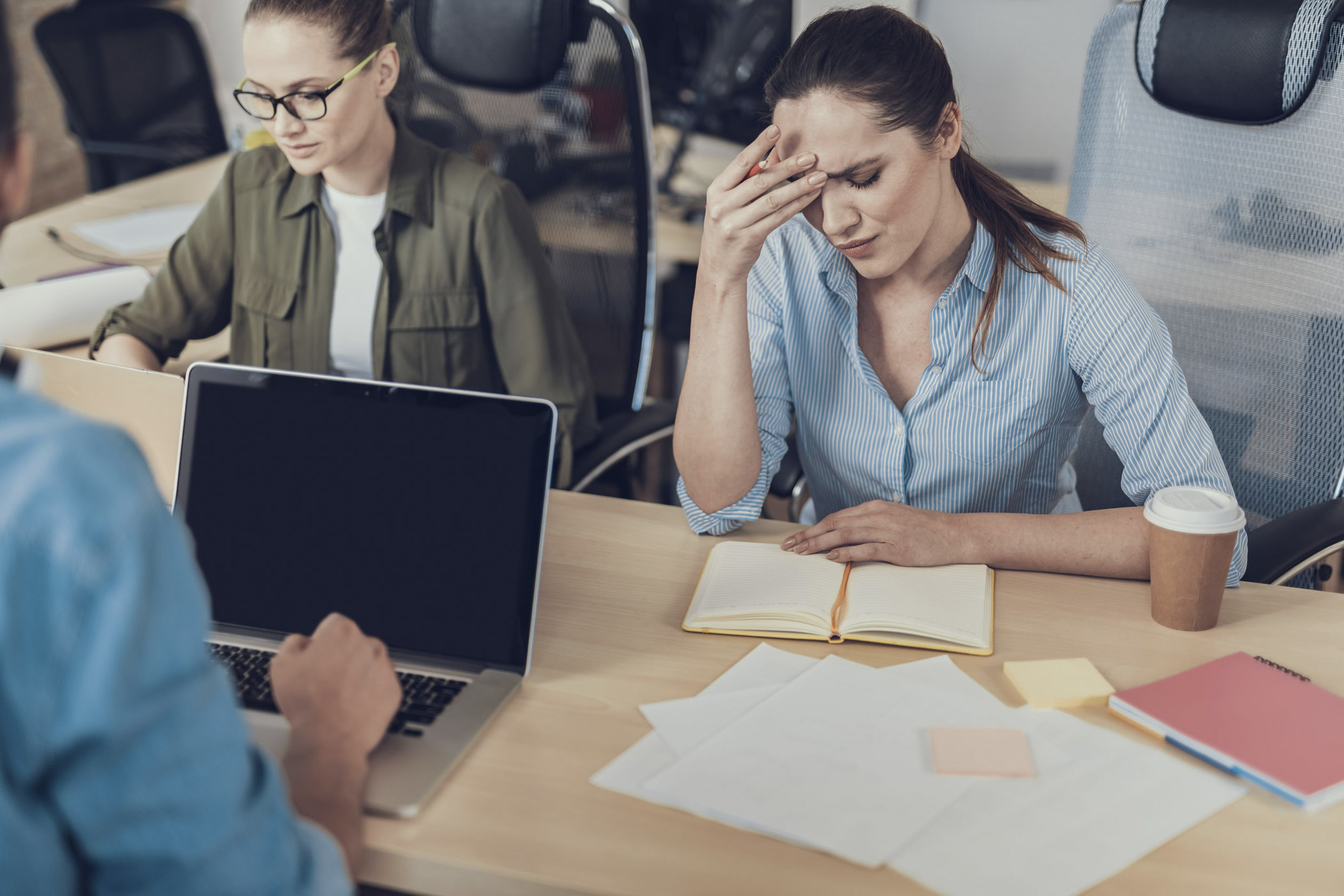 Der innerliche Rückzug beginnt oft mit Unzufriedenheit mit den Aufgaben im Job. Auf dem Foto: Junge Angestellte, die sich bei der Arbeit verzweifelt an den Kopf fasst.