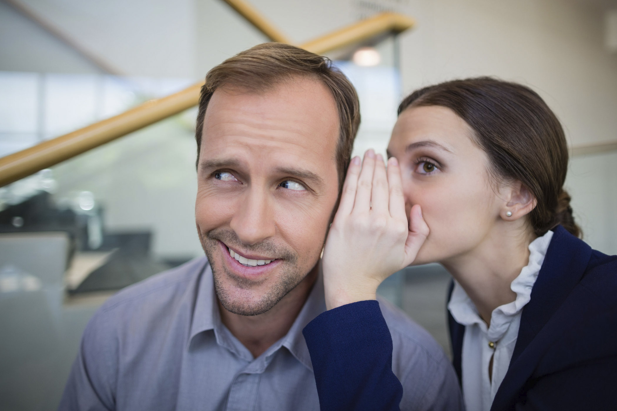 Über das eigene Gehalt muss man nicht länger hinter vorgehaltener Hand sprechen. auf dem Foto: Eine Angestellte, die ihrem Kollegen etwas ins Ohr flüstert